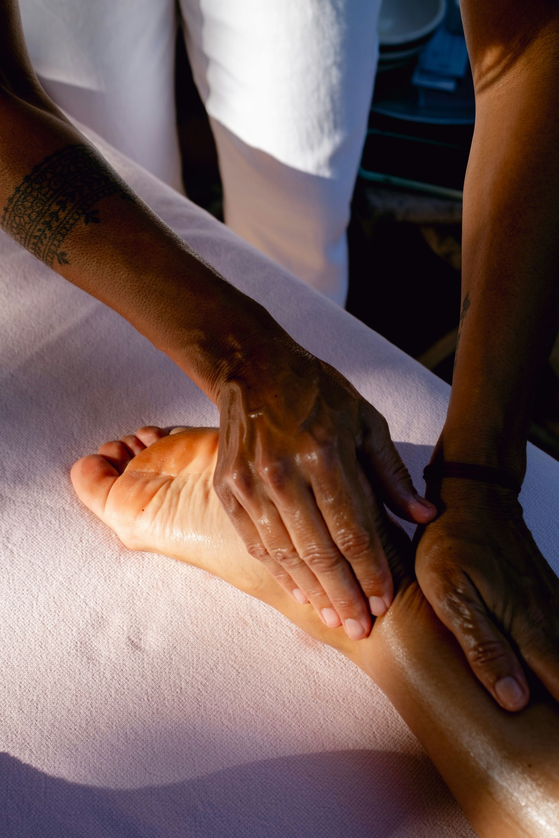 A person is doing a foot massage on a bed