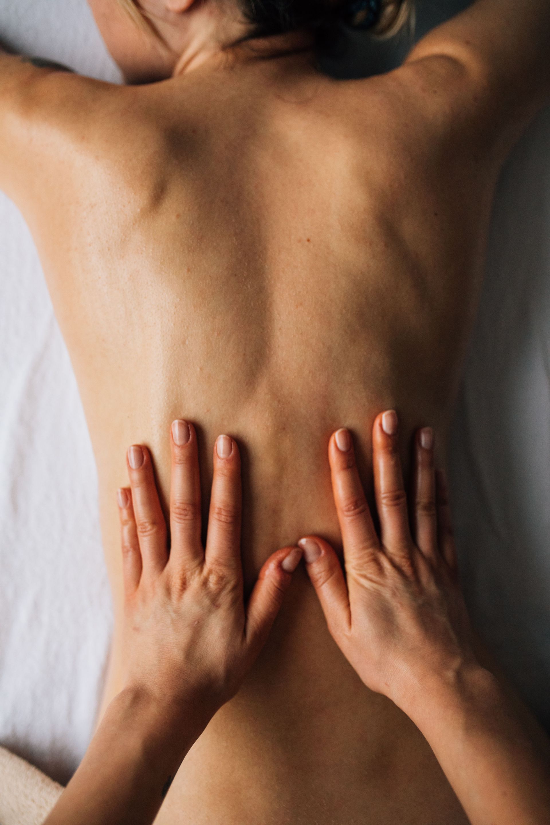 Hands massaging a person's back for relaxation in a calming indoor setting.
